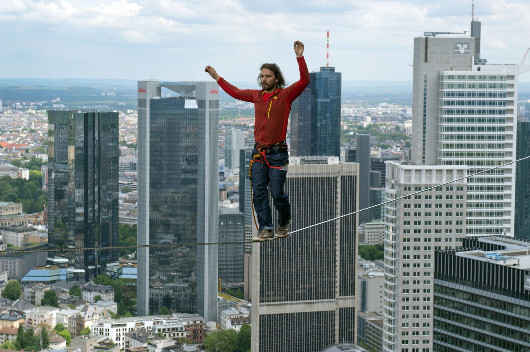 Der aus Österreich stammende Profi-Slackliner Reinhard Kleindl überwindet in rund 185 Metern Höhe auf einem Slackline-Seil die Strecke zwischen zwei Türmen des "Tower 185" in Frankfurt am Main. Dabei ist im Hintergrund die Bankenskyline des Mainmetropole zu sehen. Foto: Boris Roessler/dpa