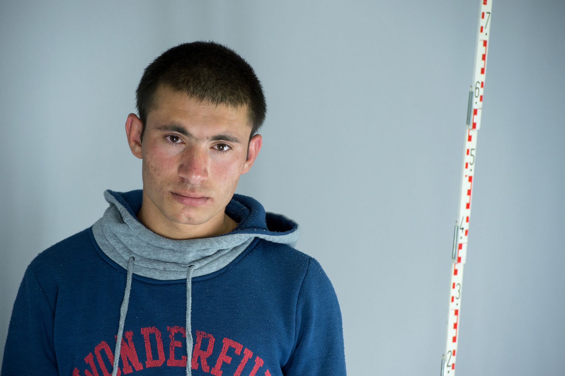 Erschöpft steht der 16-jährige Kahlil aus Afghanistan im improvisierten Befragungsraum der Bundespolizei am Hauptbahnhof in Frankfurt bei der erkennungsdienstlichen Behandlung neben einem Zentimetermass. Foto: Boris Roessler/dpa 